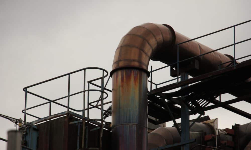 a metal pipe with rust on it near a building