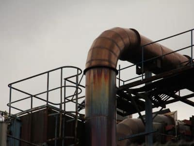 a metal pipe with rust on it near a building