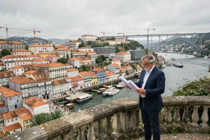 Architecte étudiant des plans devant le panorama urbain de Porto avec vue sur le Douro et des grues de construction en arrière-plan