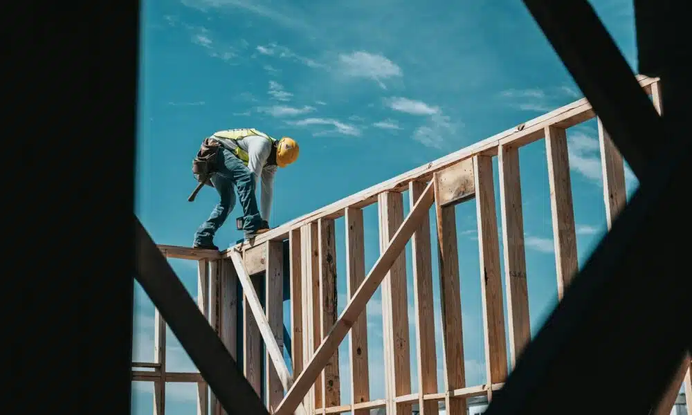 man in yellow shirt and blue denim jeans jumping on brown wooden railings under blue and