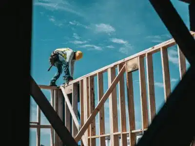 man in yellow shirt and blue denim jeans jumping on brown wooden railings under blue and