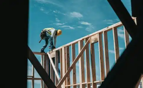 man in yellow shirt and blue denim jeans jumping on brown wooden railings under blue and